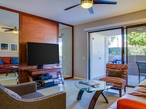 A modern living room with a flat-screen TV, a glass coffee table, and a sofa.