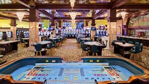 A casino with multiple slot machines, tables, and a large craps table.