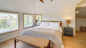 Ein Schlafzimmer mit einem großen Bett, Holzbalken, einer Bank und zwei Nachttischen mit Lampen.