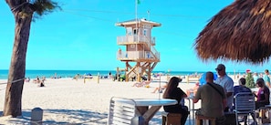 A lifeguard tower, beach chairs, and a clear blue sky.