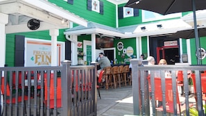 A green building with a bar area, outdoor seating, and a sign for 'FRECKLE FIN Irish Pub.'