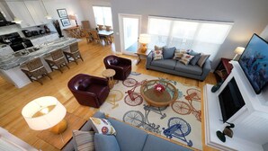 A spacious living area with a sofa, chairs, a dining table, and a kitchen in the background. - Ride the Tide – Heated Pool Home | Steps to  Holmes Beach | Heated Pool | Free WIFI & Trolley , NO Roads to Cross, Dog*(See Note)Allow (Holmes Beach)