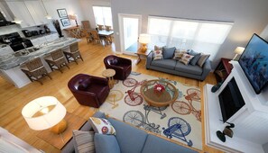A spacious living area with a sofa, chairs, a dining table, and a kitchen in the background.
