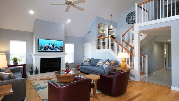 A living room with a fireplace, television, and a staircase. - Ride the Tide – Heated Pool Home | Steps to  Holmes Beach | Heated Pool | Free WIFI & Trolley , NO Roads to Cross, Dog*(See Note)Allow (Holmes Beach)