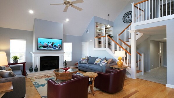 A living room with a fireplace, television, and a staircase.