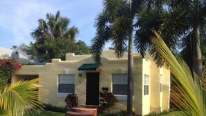 A stucco house with a green awning, a front door, and a small porch.