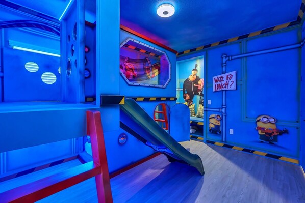 Quarto com decoração azul, um escorrega e um aviso perguntando "WANT FO LUNCH?".