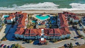 Ein Resort mit einem zentralen Pool, mehreren Gebäuden mit roten Dächern und einem Strand im Hintergrund.
