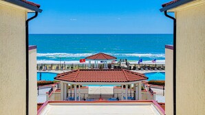 Blick auf einen Strandresort mit Pool, Pavillon und einer Pier, die ins Meer führt.
