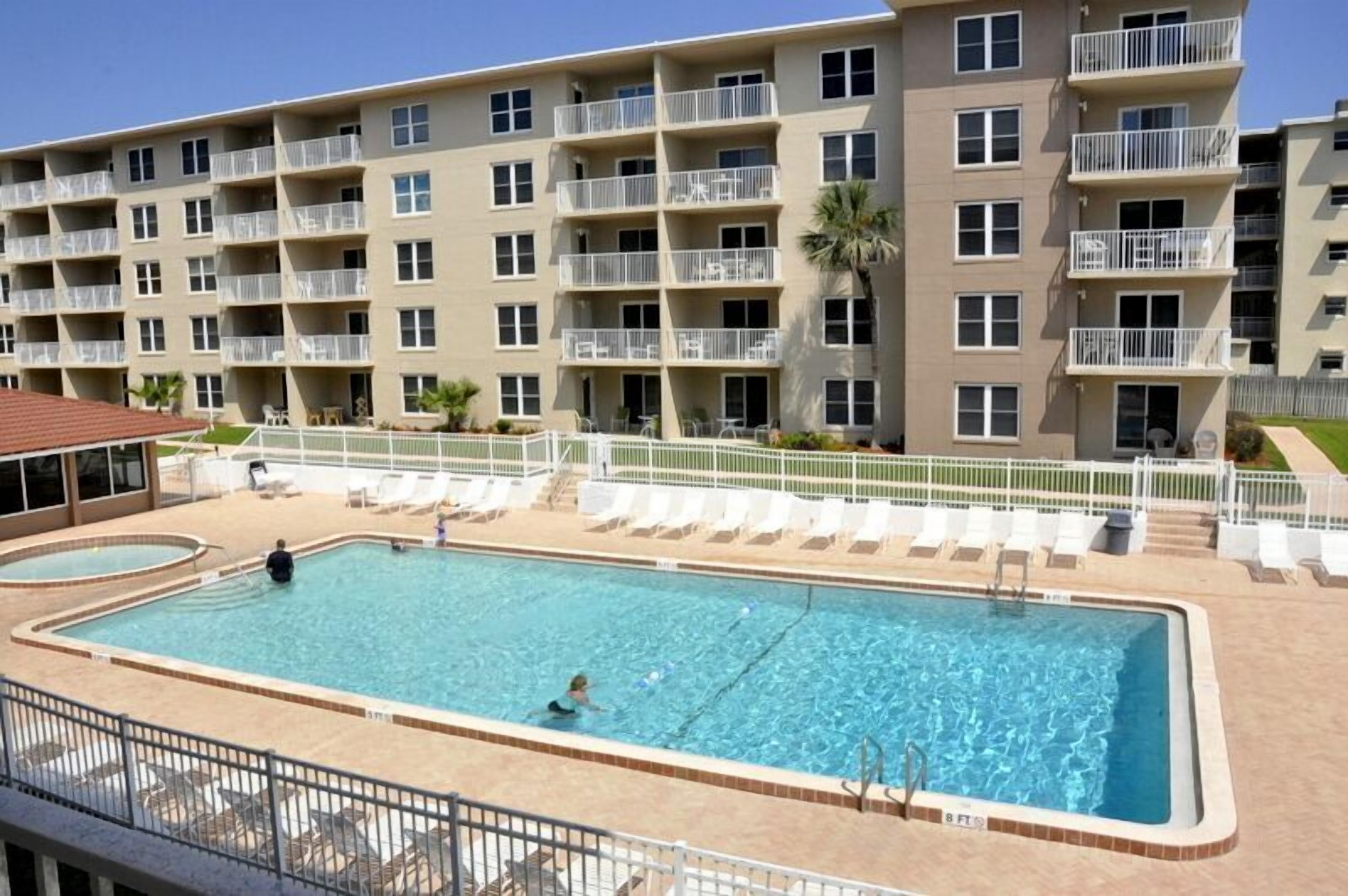 A multi-story hotel with a swimming pool, outdoor seating, and balconies.