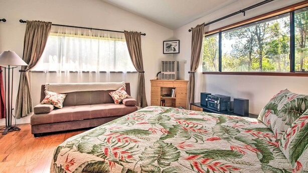 Une chambre à coucher avec un lit, un canapé, un bureau avec un ordinateur et une fenêtre avec des rideaux.