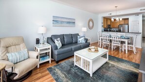A modern living room with a sofa, armchair, coffee table, and dining area. - GD 504 Emerald Sea Oasis: Wake Up to Breathtaking Ocean Views (Fort Walton Beach)
