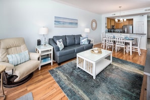 Un salon comprenant un canapé, un fauteuil, une table basse et un coin repas avec une table et des chaises.
