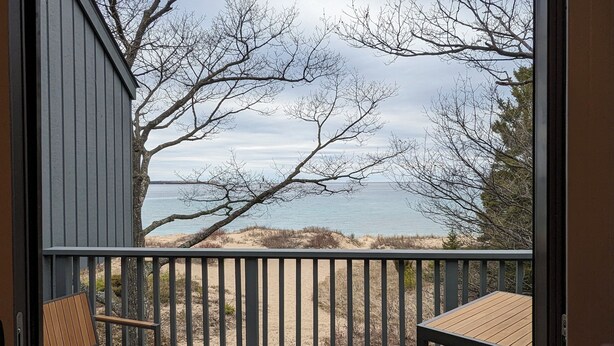 Una terraza de madera con vista a la playa y al océano.