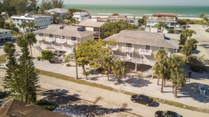 A beachfront hotel with multiple balconies, a parking area, and a view of the ocean.