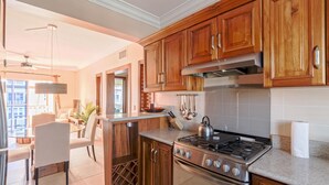 Une cuisine avec des meubles en bois, une cuisinière en acier inoxydable et un meuble à bouteilles.