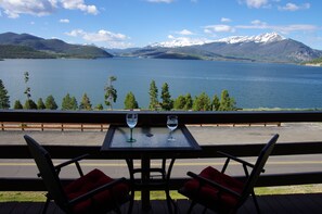 A table with two chairs and two wine glasses on a balcony overlooking a lake with mountains in the background. - Mtn-View Condo w/ Hot Tub Access in Dillon! (Dillon)