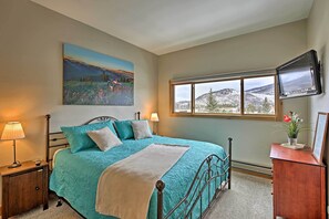 A bedroom with a bed, a painting, a TV, and a window with a mountain view. - Mtn-View Condo w/ Hot Tub Access in Dillon! (Dillon)