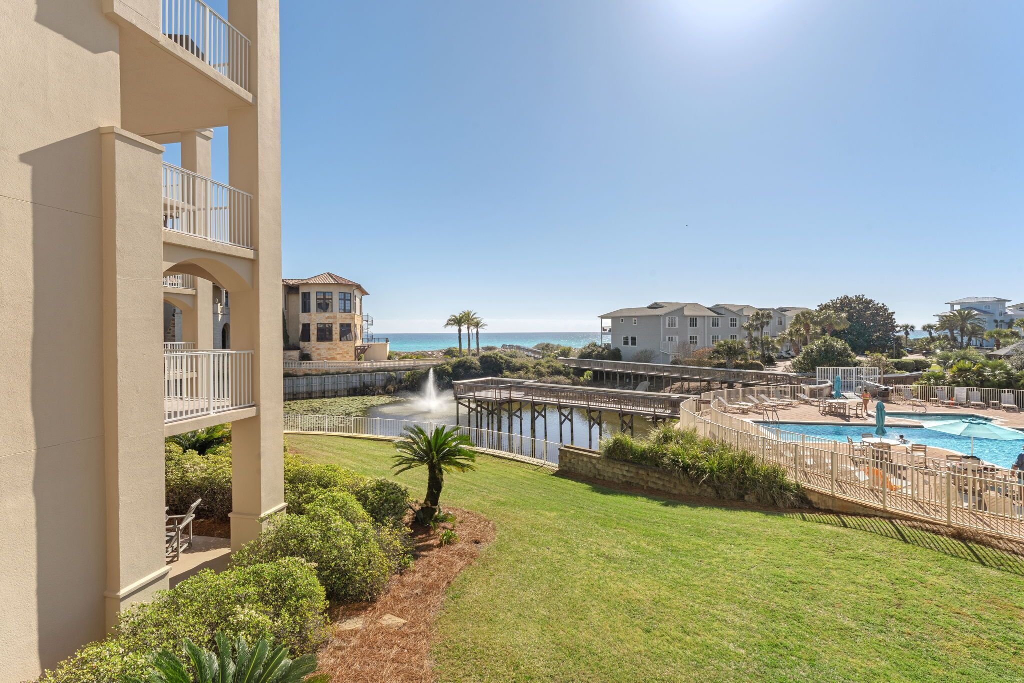 A residential building with balconies, a swimming pool, and a view of the sea.
