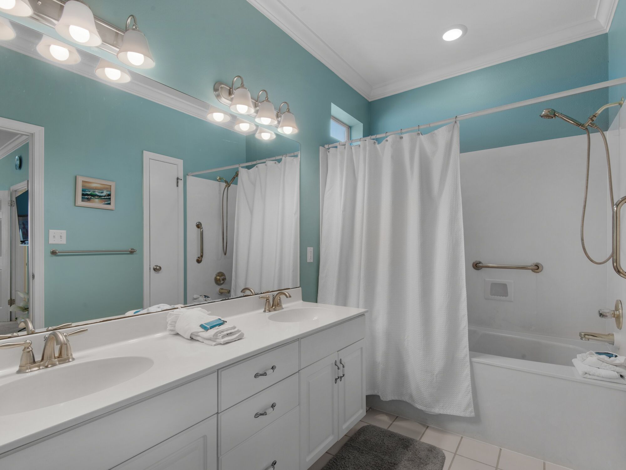 A bathroom with a white vanity, a large mirror, and a shower with a curtain.