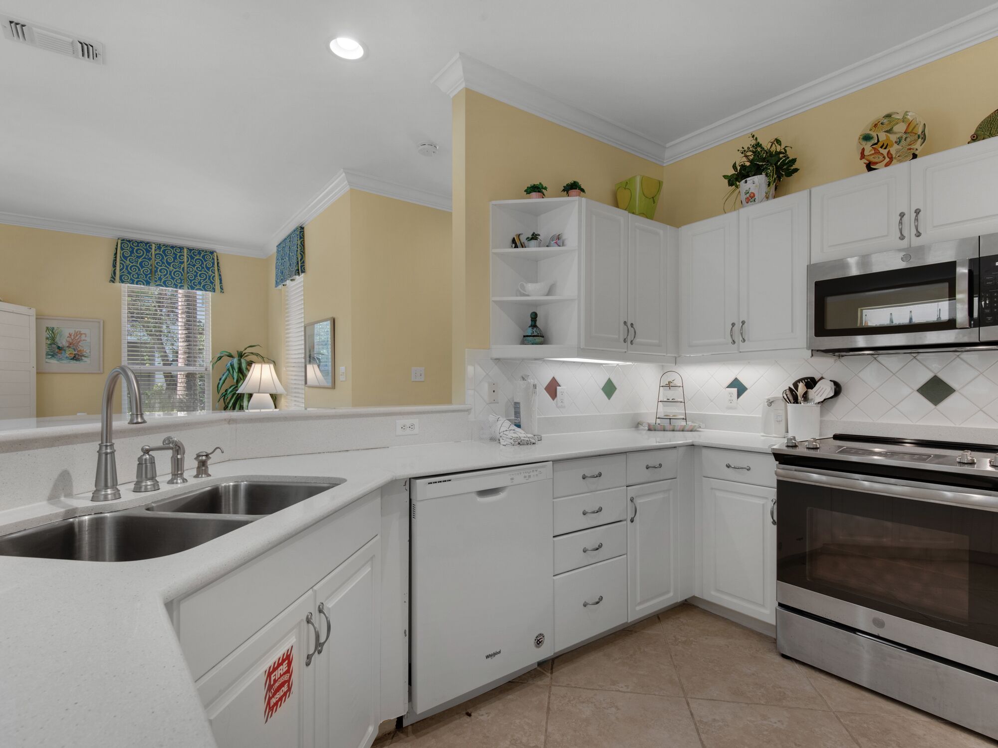A modern kitchen with white cabinetry, a stainless steel sink, and a built-in oven.