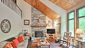 A cozy living room with a stone fireplace, a comfortable sofa, a wooden coffee table, and a television. - Relaxing Eagle Rock Resort Home - 1 Block to Lake! (Hazleton)