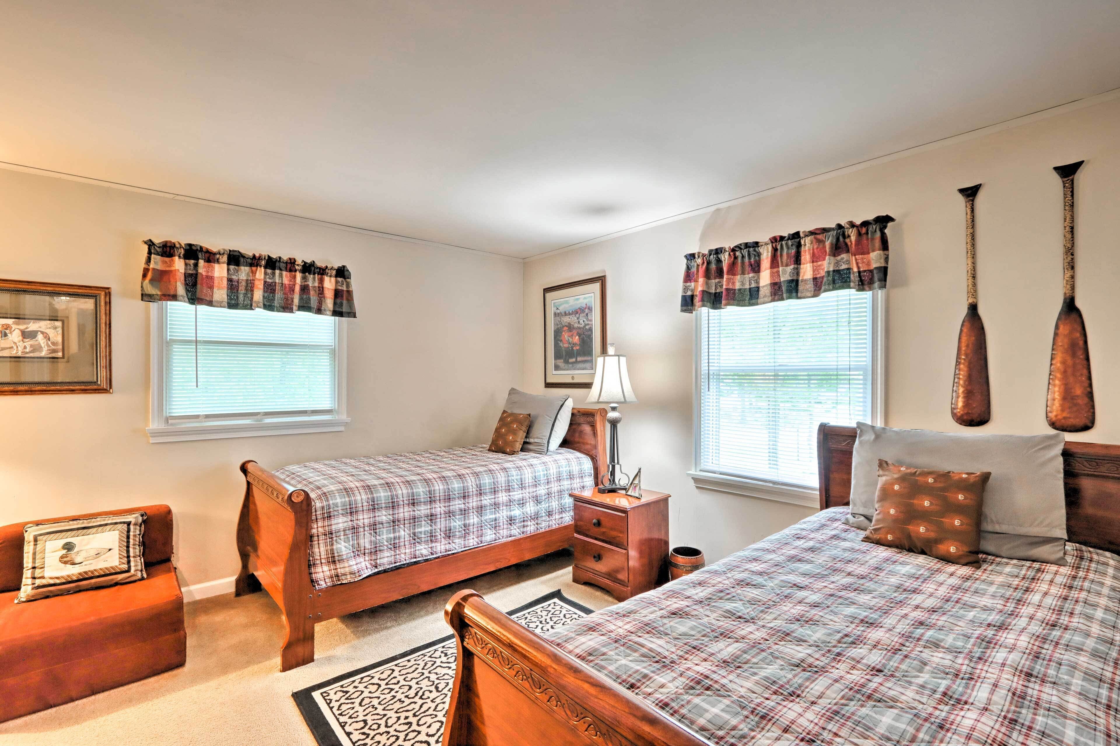 A bedroom with two beds, a nightstand, a lamp, and a window with curtains.
