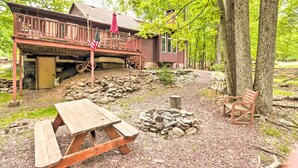 A rustic cabin with a wooden deck, a picnic table, a fire pit, and a bench. - Relaxing Eagle Rock Resort Home - 1 Block to Lake! (Hazleton)