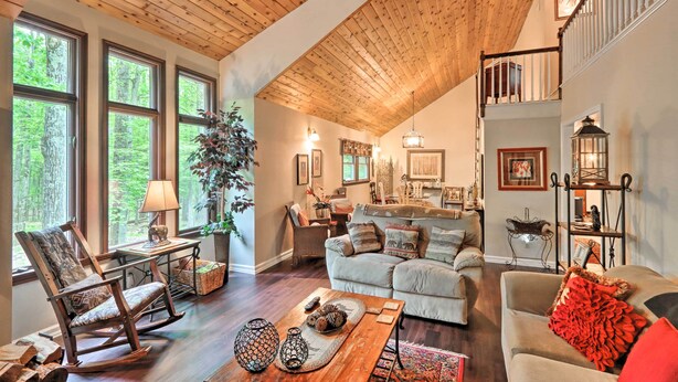A spacious living room with a high ceiling, large windows, and a cozy fireplace. - Relaxing Eagle Rock Resort Home - 1 Block to Lake! (Hazleton)