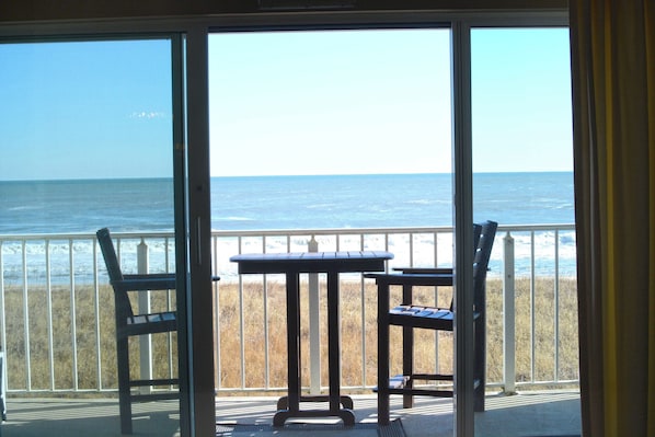 A balcony with a table and chairs overlooking the ocean. - Spacious, impeccably-styled 1 bedroom oceanfront condo with free WiFi and fabulous view of the ocean just steps to the beach! (Ocean City)
