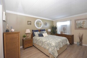 Ein Schlafzimmer mit Bett, Nachttischen, einem Schminktisch, einem Spiegel und einem Fenster mit Vorhängen.
