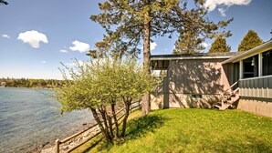 Eine Holzhütte am Seeufer mit einem Rasen, einer Holzterrasse und einem Kiesweg zum Wasser.