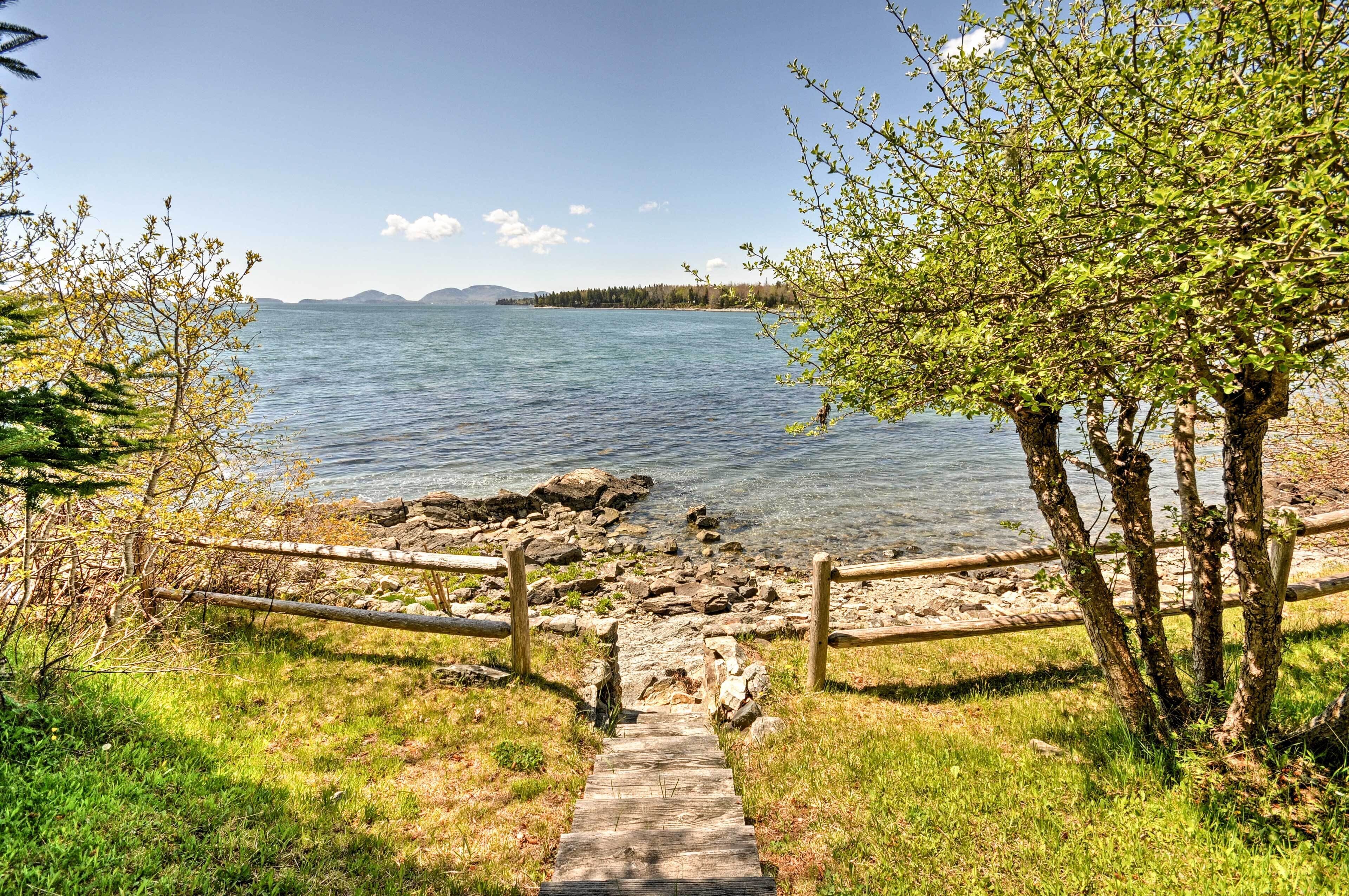 A wooden pathway leading to a lake with a clear view of the water and distant mountains.