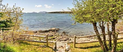 A wooden pathway leading to a lake with a clear view of the water and distant mountains.