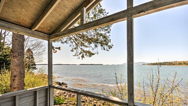 Eine Holzterrasse mit Blick auf einen See und vorgelagerte Inseln.