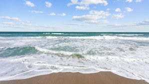 A beach with waves and a clear sky.