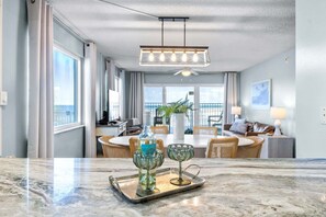 A modern hotel room with a dining area, a balcony with a view, and a ceiling fan.