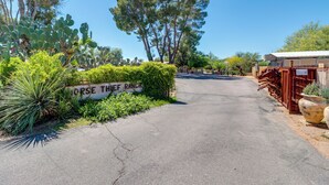 Una entrada pavimentada a una propiedad, con un letrero que dice 'HORSE THEIF RANCH'.