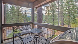A covered outdoor seating area with a metal table and chairs, overlooking a forested area. - Northstar Resort Shuttle Access: Truckee Condo (Truckee)