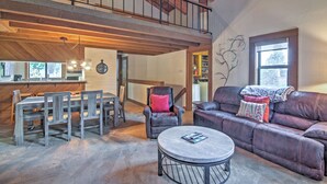 A spacious living area with a high ceiling, a dining table with chairs, a leather sofa, and a round coffee table. - Northstar Resort Shuttle Access: Truckee Condo (Truckee)