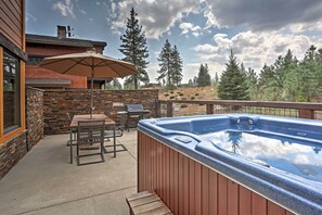 Relax in a serene outdoor space with a hot tub, shaded seating area, and breathtaking mountain views.