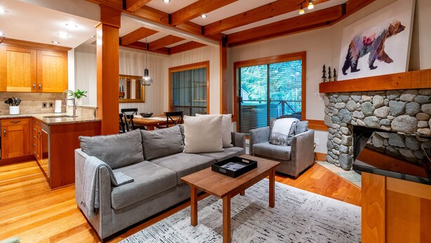 A spacious living area with a gray sofa, a wooden coffee table, and a stone fireplace.