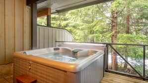 A hot tub in a wooden cabin with a view of a forest.