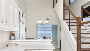 A kitchen with white cabinetry, a marble countertop, and a chandelier. - Sunroom, Quiet Neighborhood, Gulf Front, Private Dune Walkover ~ La Mer (Cape San Blas)