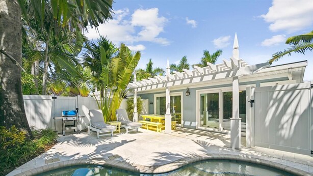 A poolside area with a barbecue grill, lounge chairs, and a covered patio.
