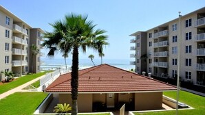 A beachfront hotel with a red-roofed building, palm trees, and ocean views. - Cute 2/2!Direct Oceanfront Complex on the No Drive Beach in NSB! (New Smyrna Beach)