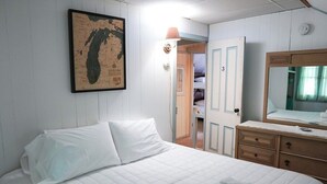 Ein Hotelzimmer mit einem Bett, einer Karte an der Wand, einem Schminktisch und einer Tür zu einem anderen Raum.
