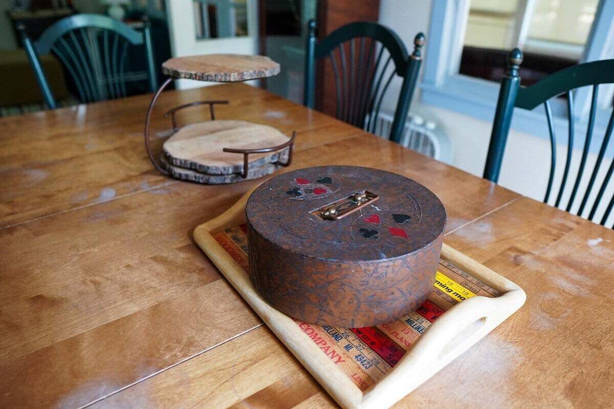 A round, rustic cheese wheel on a wooden table with a newspaper underneath.