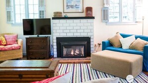Ein Wohnzimmer mit Kamin, Fernseher, einer Couch und einem gemusterten Teppich.
