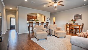 A spacious living room with a high ceiling fan, hardwood flooring, and a neutral color palette.